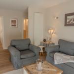 Wohnzimmer mit grauem Sofa und Sessel, Holzboden und Wandbild.