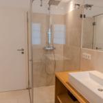 Badezimmer mit Dusche, Waschbecken und Spiegel.