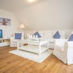 Wohnzimmer mit weißem Sofa, Holzboden und Fernseher