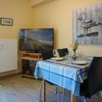 Essbereich mit Tisch, Stühlen und Fernseher an der Wand.