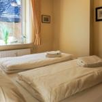 Zimmer mit zwei Betten, Fenster mit Vorhängen und Wandbildern.