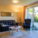 Wohnzimmer mit Sofa, Sessel und Glastür zur Terrasse.