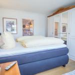 Schlafzimmer mit Bett, Kleiderschrank und Nachttisch.