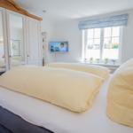 Schlafzimmer mit Doppelbett, Spiegelschrank und Fenster mit Blenden.