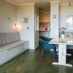 Dining area with table, chair, and sofa. Green tiled floor and white walls.