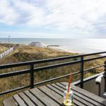 Terrace with table and chair offers view of beach and sea.