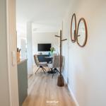 Hallway with two round mirrors and view into living area with table and chairs.