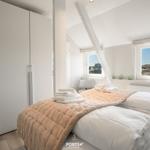 Bedroom with double bed, white walls, and window view of landscape.