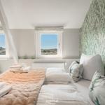 Bedroom with view of the landscape, comfortable bed and patterned wallpaper.