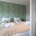 Bedroom with bed, pillows, and floral wallpaper on the wall.