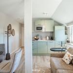 Living area with sofa, kitchenette, and dining space. Window view of landscape.