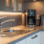 Küchenzeile mit Spüle, Kaffeemaschine und Wasserkocher.