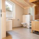 Badezimmer mit Toilette, Waschbecken und Sauna im Holzdesign.