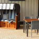 Terrasse mit Liegestuhl und Esstisch mit Stühlen.