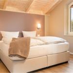 Schlafzimmer mit Doppelbett, Holzdecke und Fenster. Neben dem Bett steht ein Nachttisch.