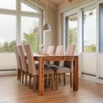 Esszimmer mit Holztisch, sechs Stühlen und großen Fenstern zur Aussicht.