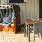 Terrasse mit Liegestuhl und Esstisch mit Stühlen.