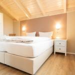Schlafzimmer mit Doppelbett, Nachttisch und Holzdecke.