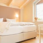 Schlafzimmer mit Doppelbett, Holzdecke und Fenster mit Blick.