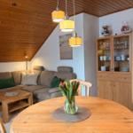 Wohn- und Essbereich mit Holzdecke, Sofa, Esstisch und Sideboard.