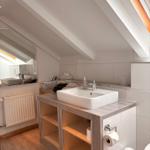 Badezimmer mit Waschbecken, Spiegel und Dachfenster.