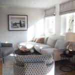 Wohnzimmer mit Sofa, Sessel und Fenstern.