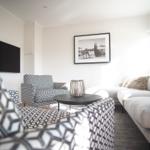 Wohnzimmer mit Sofa, Sessel und Fernseher an der Wand.