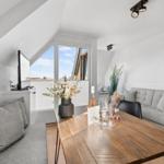 Wohnzimmer mit Sofa, Esstisch und TV unter Dachschrägen.
