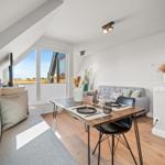 Essbereich mit Tisch, Stühlen und Sofa. Fenster mit Blick auf Außenbereich.