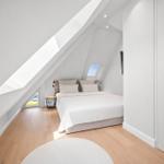 Schlafzimmer mit Dachschrägen, weißem Bett und Holzboden