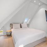Schlafzimmer mit Dachschrägen, Bett, Fenster und Fernseher.
