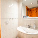Badezimmer mit Waschbecken, Spiegel und Holztür