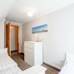 Zwei Betten, weißer Schrank, Wandbild und Tür im Dachgeschosszimmer.