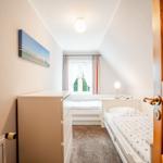 Schlafzimmer mit Dachschräge, zwei Betten und Fenster mit Vorhängen.