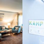 Wohnzimmer mit Sofa, Sessel und Tisch. Wandtafel mit KAMPEN.