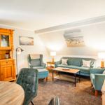 Wohnzimmer mit Sofa, Sesseln und Holzmöbeln unter Dachschrägen.