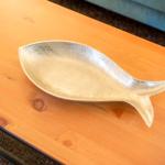 Ein silbernes Fischschale-Objekt auf einem Holztisch.