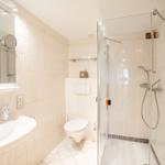Badezimmer mit Dusche, Toilette und Waschbecken.