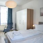 Schlafzimmer mit Bett, Kleiderschrank und Fenster mit Vorhängen.