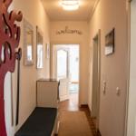 Hausflur mit rotem Baumdekoration, Spiegel und welcome-Schild.