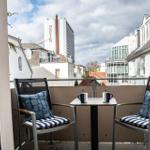 Balcony with two chairs and table, overlooking city buildings including a tower with NEPTUN sign.