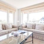 Two sofas with cushions are positioned in front of large windows with a view of the landscape.