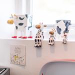 Kitchen window with cow figurines and wall decoration.