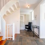 House with staircase, seating area, and table in hallway.