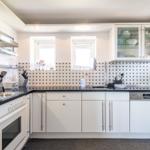 Kitchen with white cabinets, black countertop, and two windows.