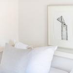 Bed headboard with pillows and framed drawing on the wall