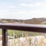 View from balcony over hills with grass and houses in the background.