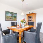 Dining table with six chairs and wooden cabinet against the wall.