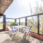 Terrace with table and chairs, view of lighthouse and greenery.