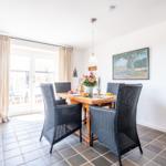 Dining room with wooden table, four chairs, and view to terrace.